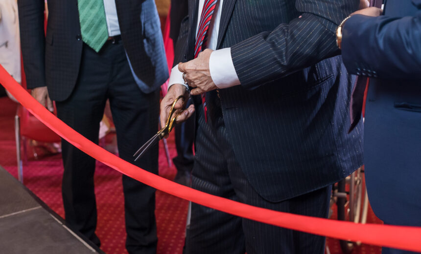 Cutting a red ribbon with scissors for new business venture or opening ceremony